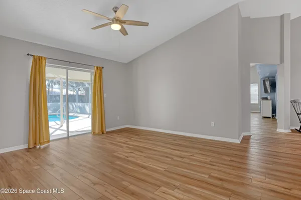 a view of empty room with wooden floor and fan