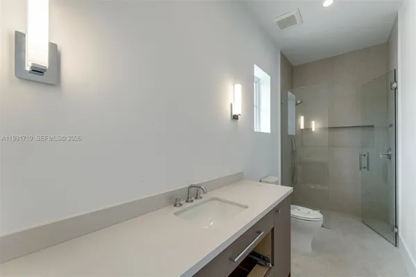 a bathroom with a granite countertop sink a toilet and shower