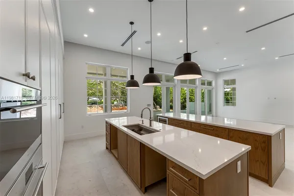 a kitchen with kitchen island a large counter top space a sink stainless steel appliances and windows