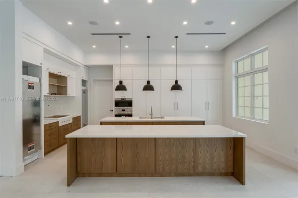 a large kitchen with stainless steel appliances a large counter top a refrigerator and a sink