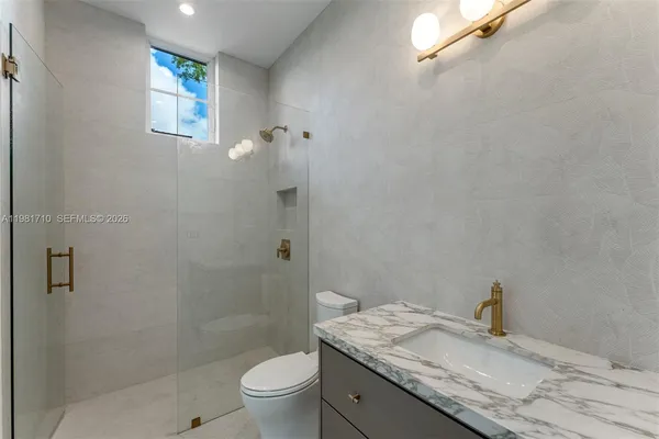 a bathroom with a granite countertop sink a toilet and shower