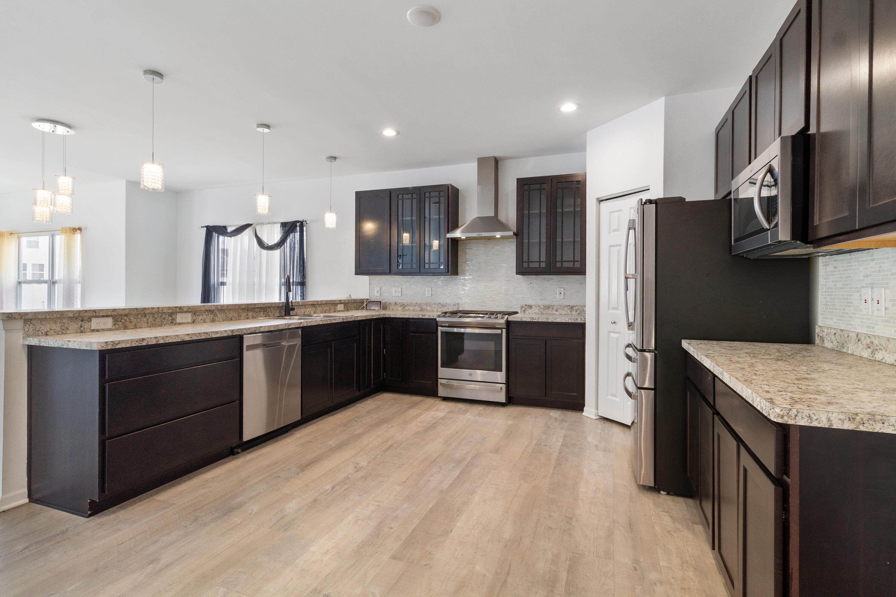 7485 Clark Street Merrillville, IN 46410 - Photo 4 of 26 a large kitchen with stainless steel appliances kitchen island granite countertop a stove refrigerator and cabinets