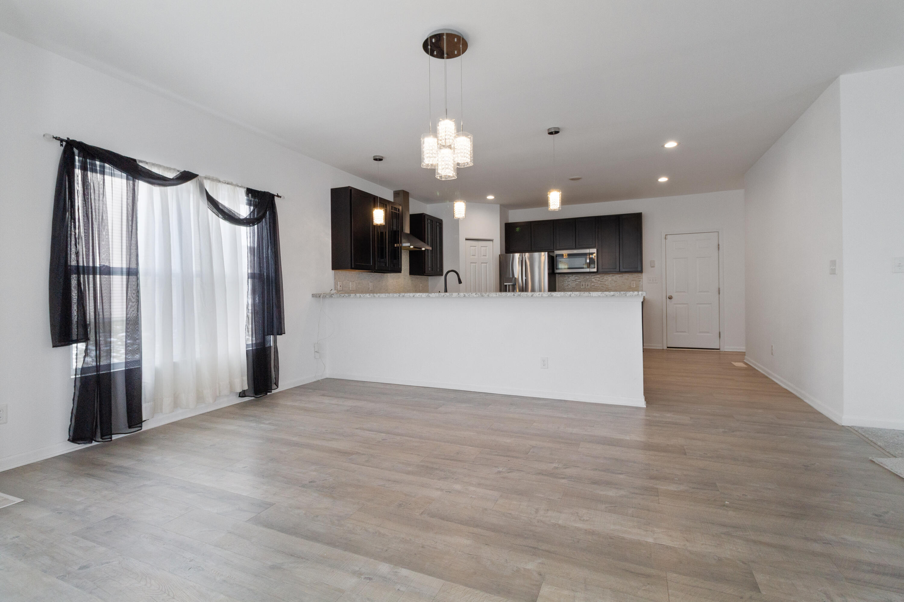 7485 Clark Street Merrillville, IN 46410 - Photo 8 of 26 a view of a kitchen with a refrigerator a ceiling fan and wooden floor