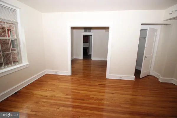 a view of an empty room with wooden floor and a window