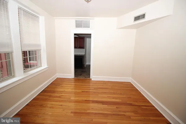 a view of an empty room with wooden floor and a window