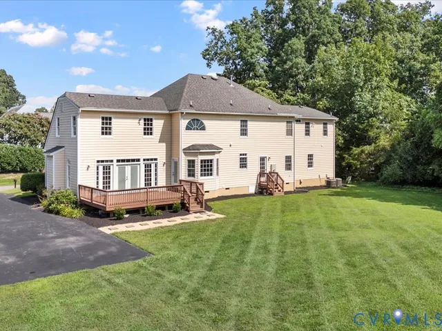 a view of a white house with a big yard and large trees