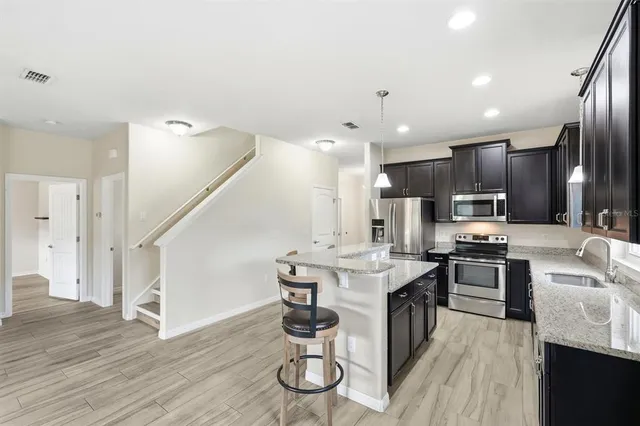 a large kitchen with stainless steel appliances kitchen island granite countertop a large stove a sink dishwasher a dining table and chairs