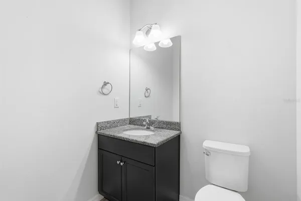 a spacious bathroom with a granite countertop sink a toilet a mirror and shower