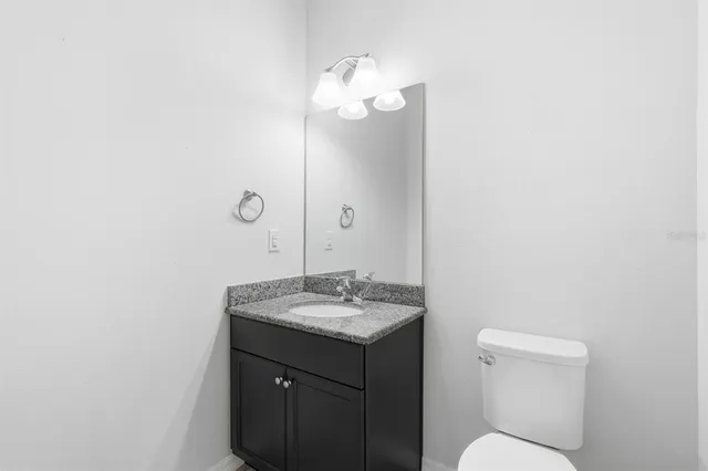 a spacious bathroom with a granite countertop sink a toilet a mirror and shower
