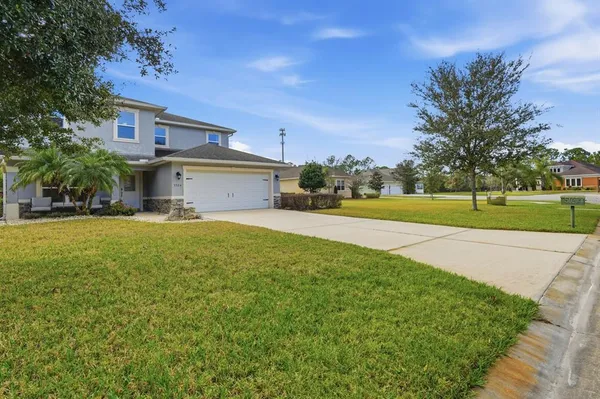 a view of a house with a big yard and palm trees