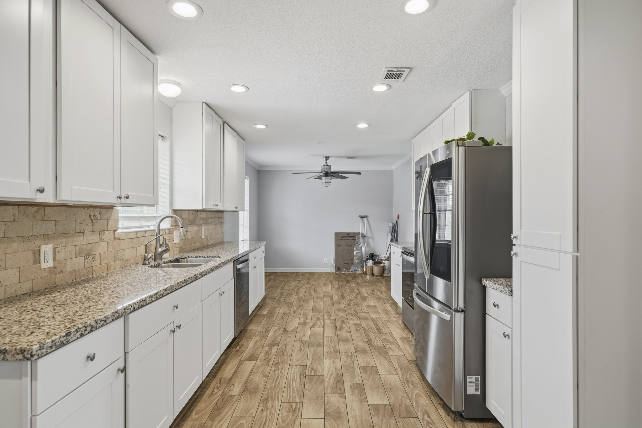 302 Country Road 893 Angleton, TX 77515 - Photo 13 of 26 This kitchen features sleek granite countertops, stainless steel appliances, and ample white cabinetry. The wood-look flooring and recessed lighting create a warm, inviting atmosphere.