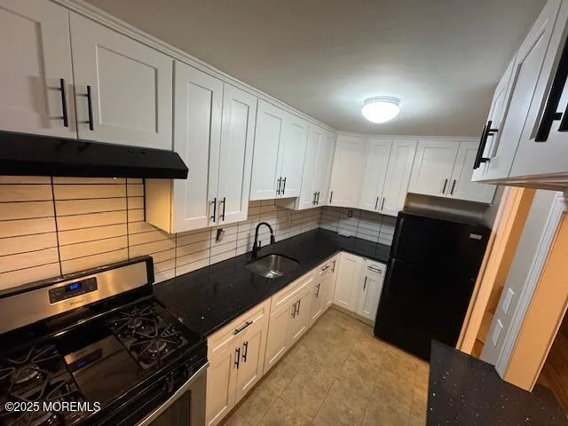 a kitchen with granite countertop a refrigerator stove and sink