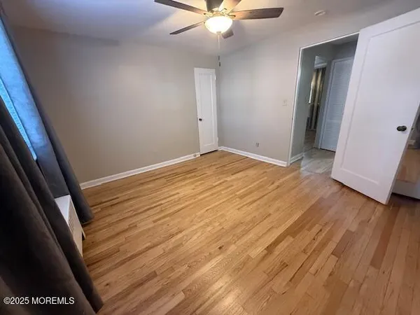 an empty room with wooden floor and fan