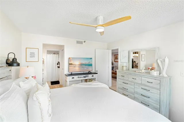 a bedroom with a bed and a flat tv screen on dresser