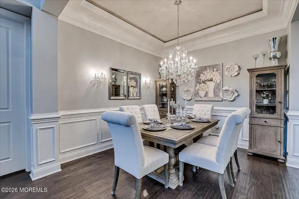 a dining room with wooden floor a chandelier a wooden table and chairs