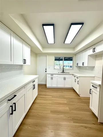a large white kitchen with wooden floors and white cabinets