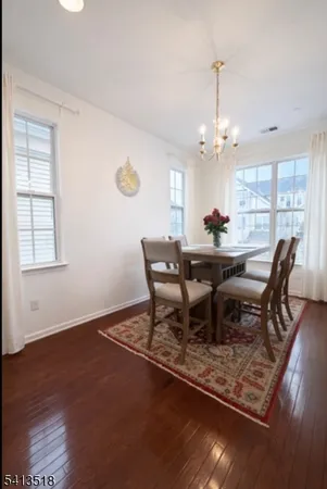 a dining room with wooden floor a chandelier a wooden table and chairs