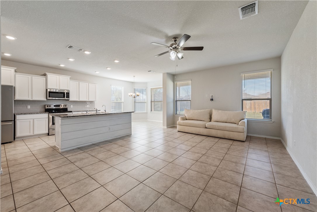 1129 Ibis Falls Loop Jarrell, TX 76537 - Photo 15 of 39 a large white kitchen with kitchen island granite countertop a stove a sink a chimney and a dining table