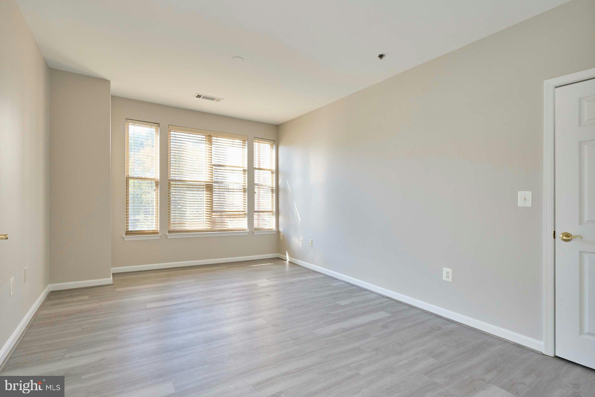 1851 Stratford Park Place, Unit 212 Reston, VA 20190 - Photo 18 of 40 a view of an empty room with wooden floor and a window