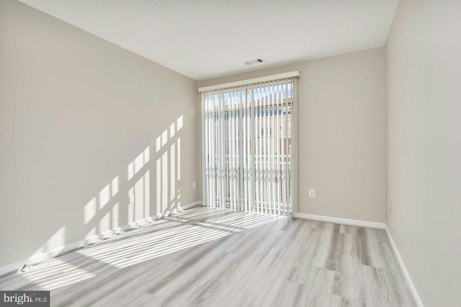 1851 Stratford Park Place, Unit 212 Reston, VA 20190 - Photo 22 of 40 an empty room with wooden floor and windows