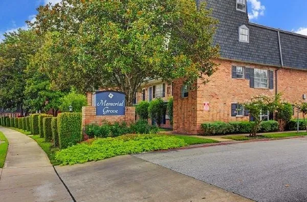 a brick building with a small yard and a large trees