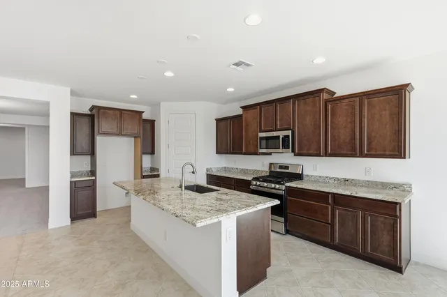 a kitchen with stainless steel appliances granite countertop a stove sink microwave and refrigerator