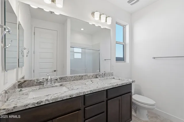 a bathroom with a granite countertop sink a toilet and a mirror