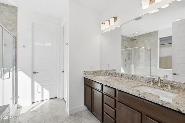 a bathroom with a granite countertop sink a mirror and a shower