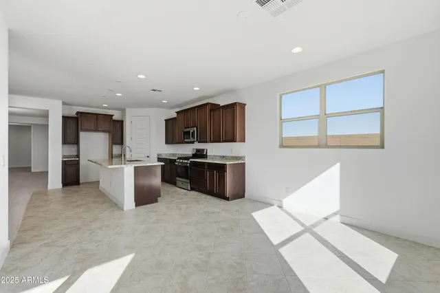 a kitchen with stainless steel appliances kitchen island granite countertop a refrigerator and a sink