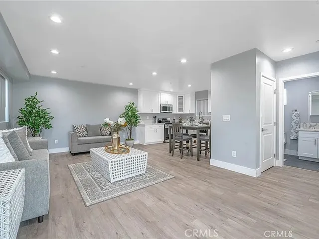 a living room with furniture potted plant and kitchen view