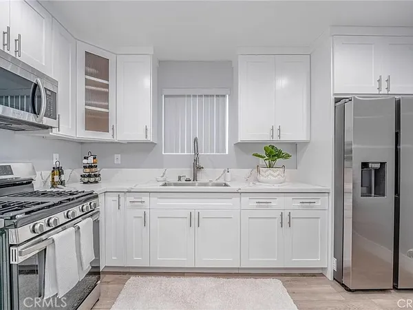 a kitchen with stainless steel appliances granite countertop a refrigerator a stove a sink and white cabinets