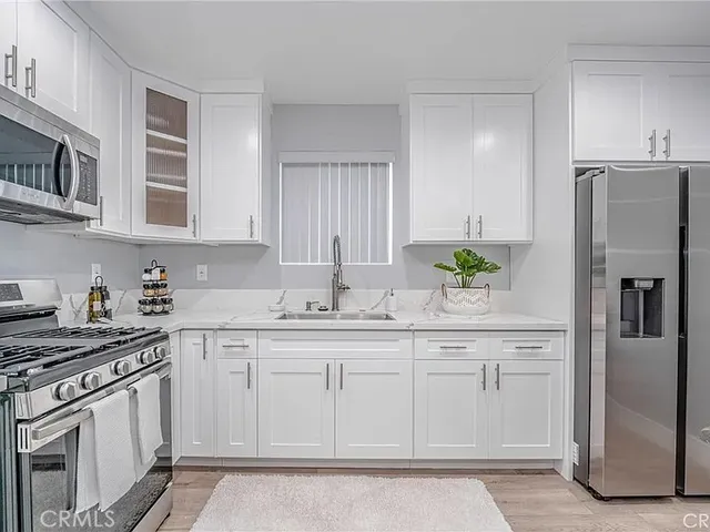 a kitchen with stainless steel appliances granite countertop a refrigerator a stove a sink and white cabinets