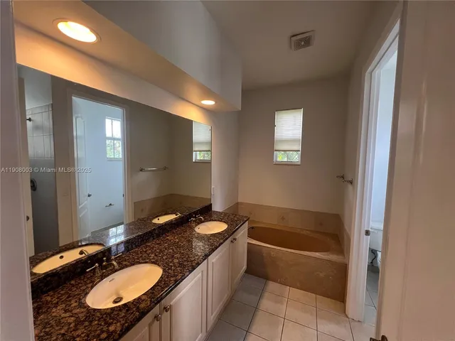 a bathroom with a granite countertop sink tub and a mirror