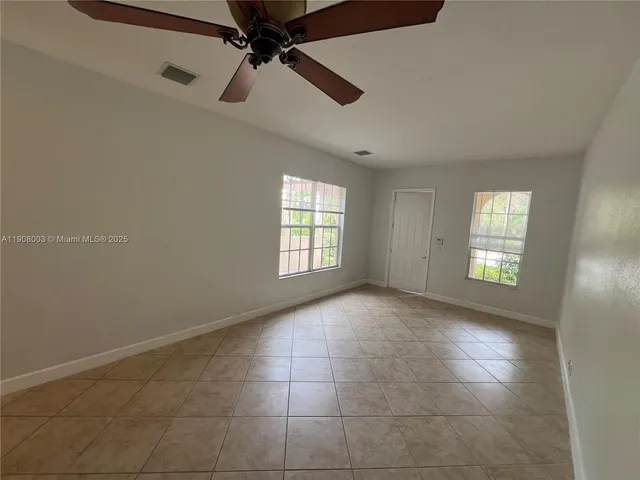 an empty room with windows and fan