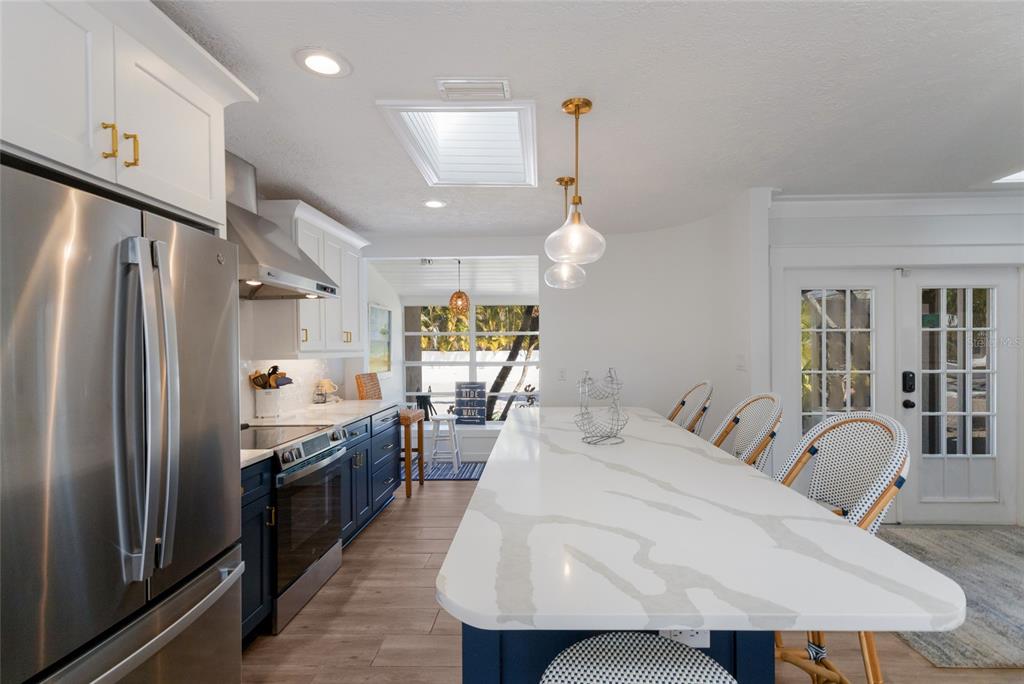 419 Clark Drive Holmes Beach, FL 34217 - Photo 19 of 53 a large kitchen with stainless steel appliances kitchen island granite countertop a refrigerator a stove a sink dishwasher with a dining table and chairs