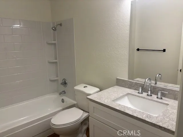 a bathroom with a granite countertop toilet a sink and a bathtub
