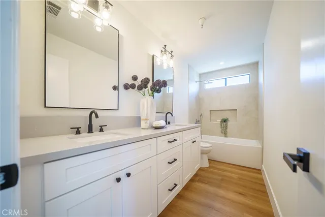 a bathroom with a double vanity sink a mirror and a bathtub