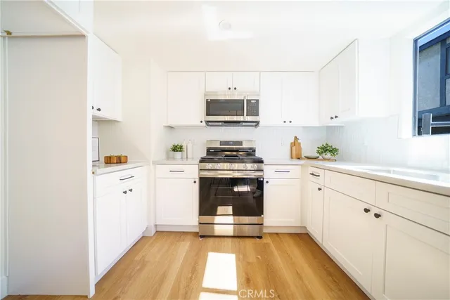 a kitchen with cabinets stainless steel appliances and a window