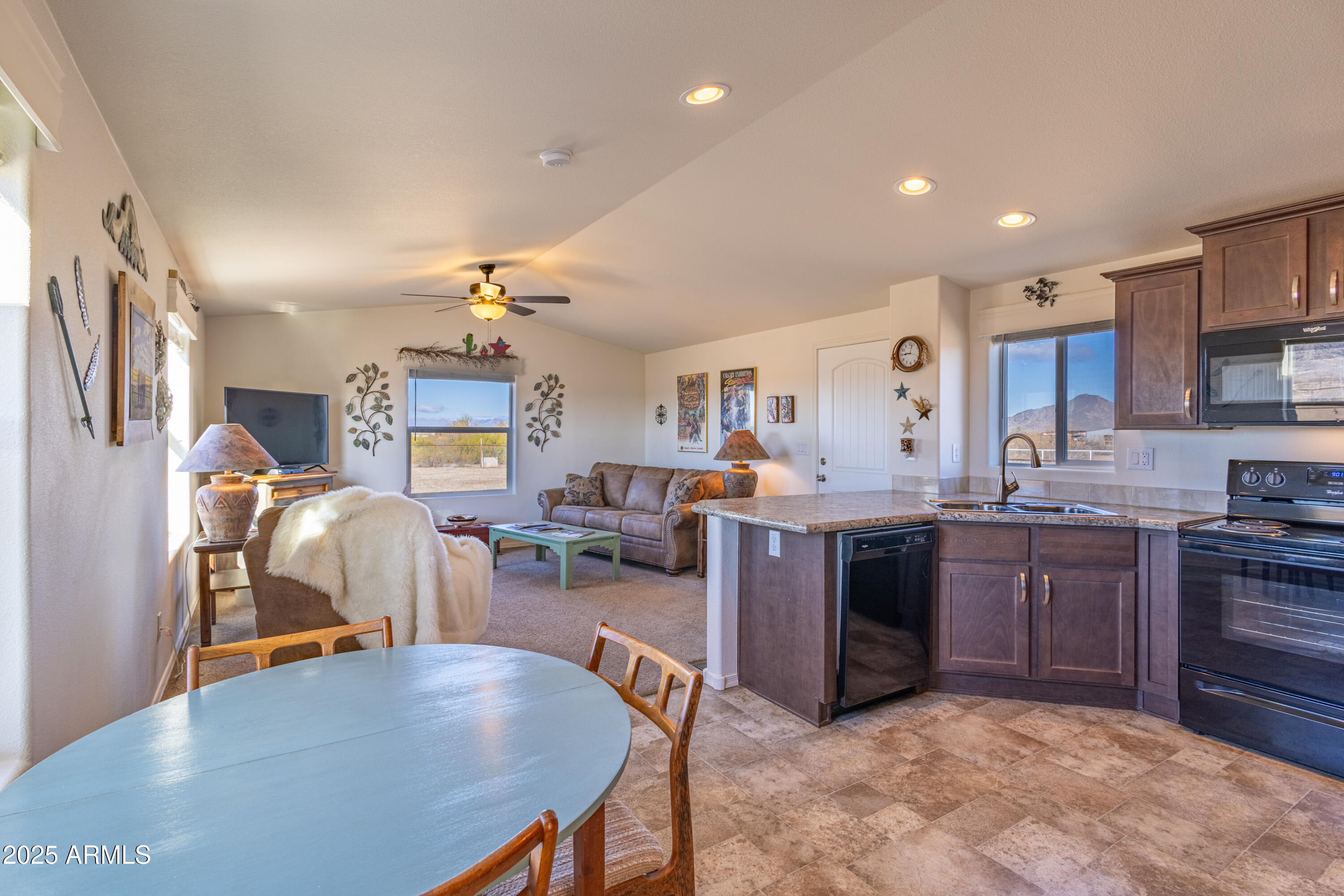 45409 West Luray Road Wickenburg, AZ 85390 - Photo 5 of 26 a kitchen with stainless steel appliances granite countertop a sink dishwasher stove top oven a dining table and chairs with wooden floor