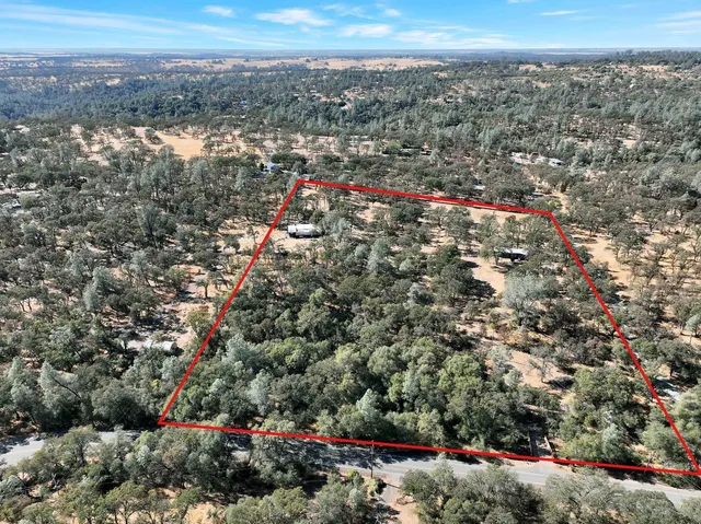 an aerial view of house with yard and mountain view in back