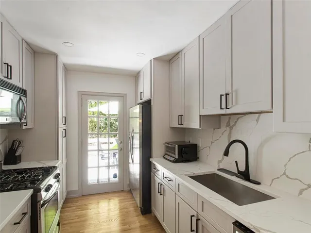 a kitchen with stainless steel appliances granite countertop a sink a stove and a wooden cabinets