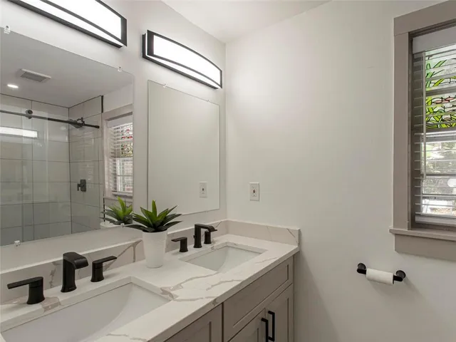 a bathroom with a granite countertop sink a mirror and a shower