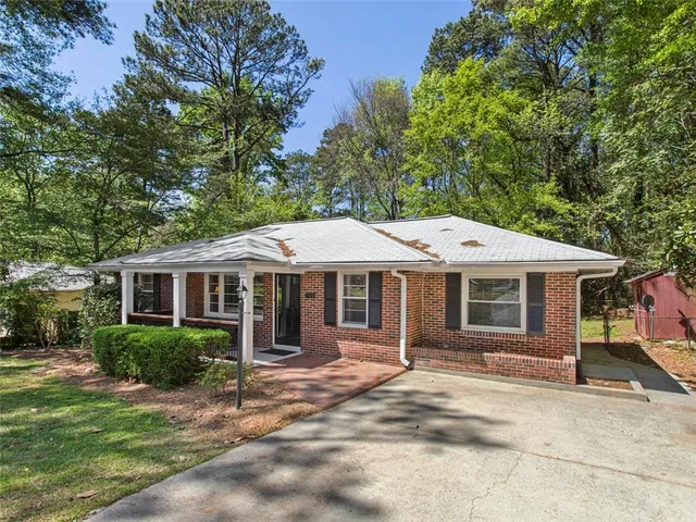 a view of a house with a yard plants and large tree
