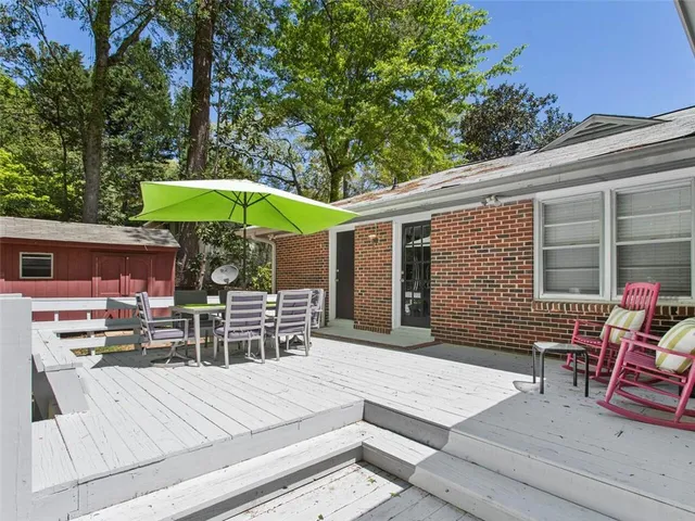 a view of a patio with table and chairs under an umbrella with barbeque grill and wooden fence