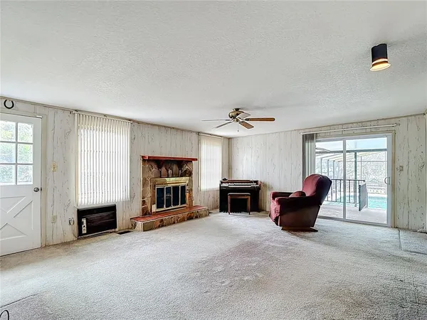 an empty room with chandelier fan and windows