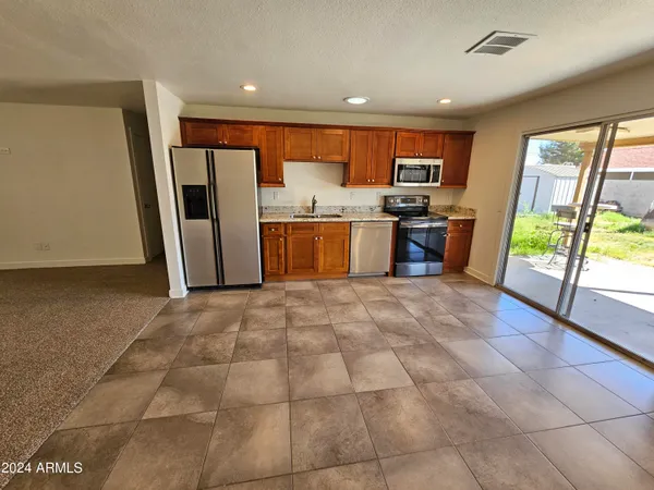 a large kitchen with stainless steel appliances granite countertop a refrigerator and a sink