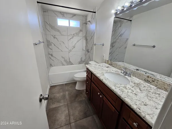 a bathroom with a granite countertop sink a toilet and shower