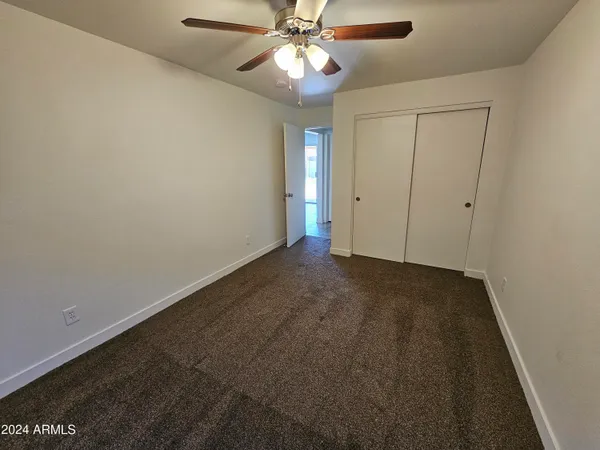 a view of an empty room and chandelier fan