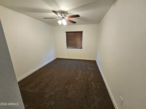 an empty room with a chandelier fan and windows