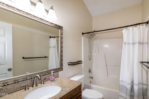 a bathroom with a granite countertop sink toilet a mirror and shower